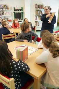 bibliothécaire explique un jeu aux enfants dans la bibliothèque jeunesse